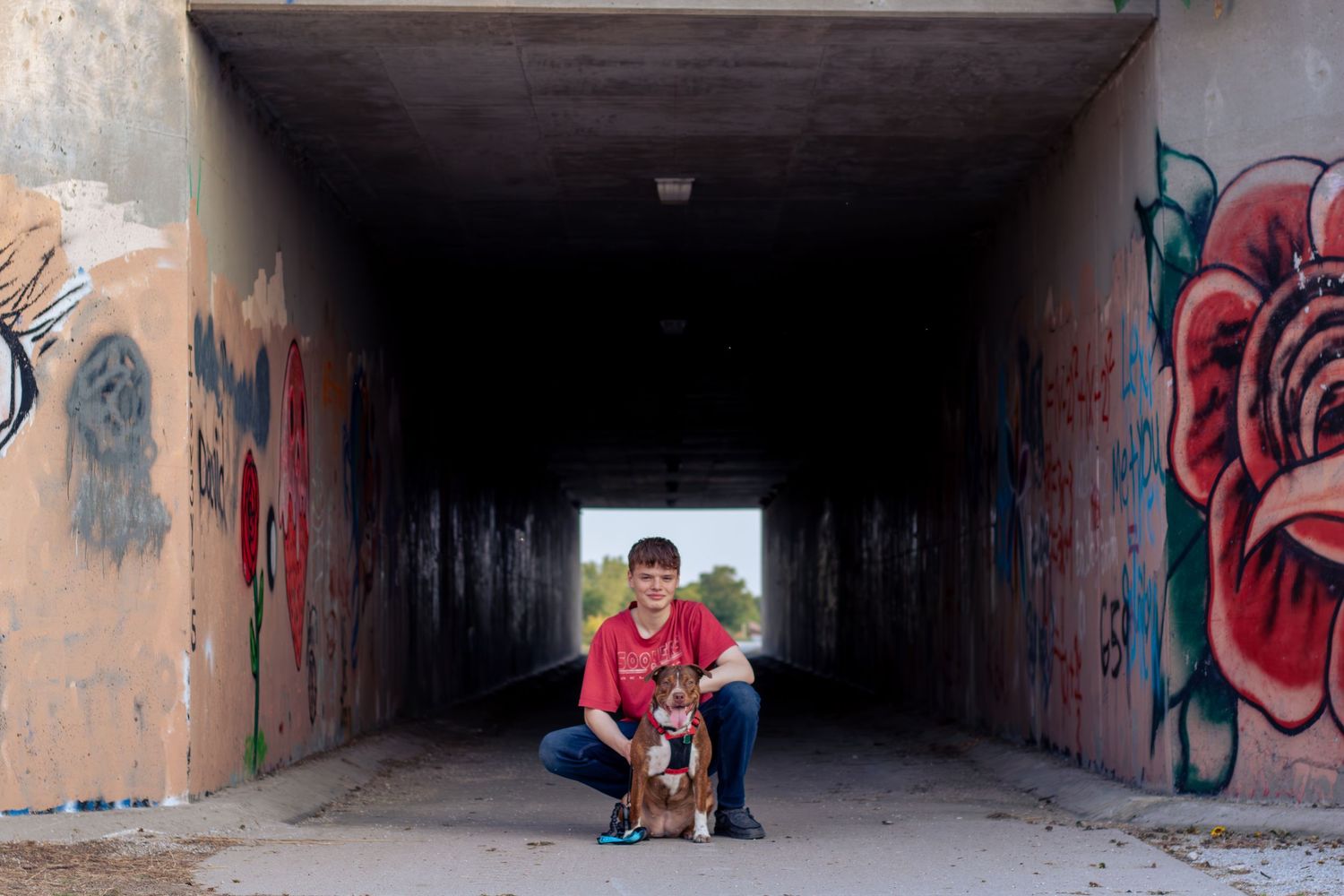 High school senior poses with dog under overpass for graduation pictures in Kearney, NE.
