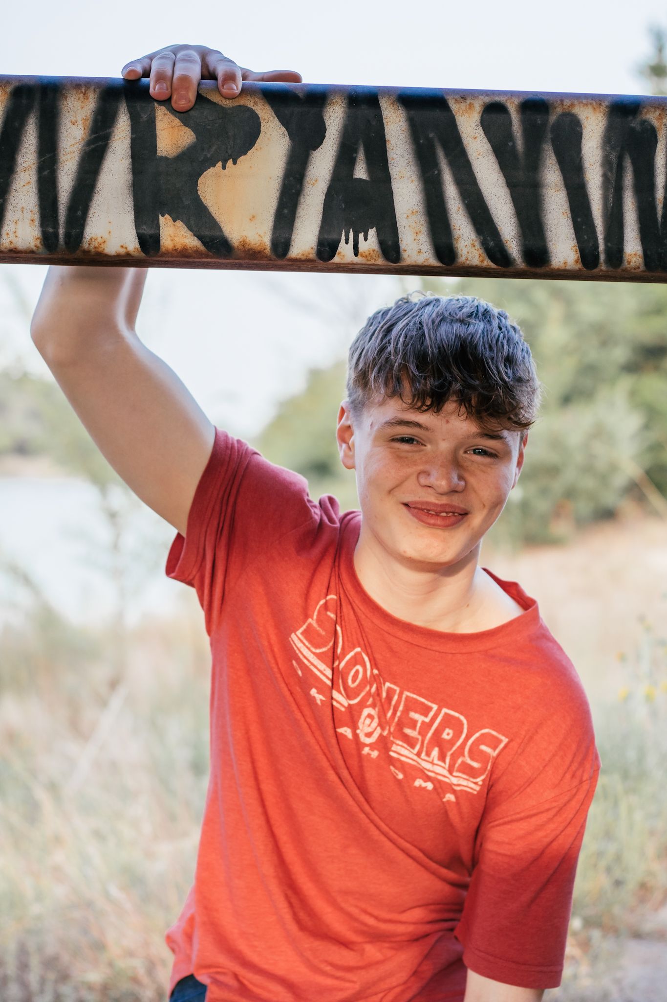 High school senior male smiles under bridge for senior session by best outdoor senior photo location in Kearney, NE.