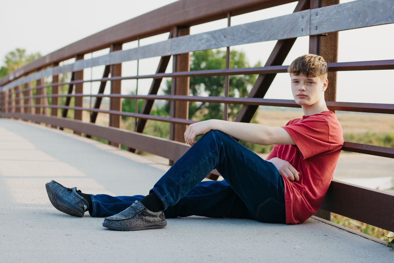 High school senior leans against bridge for senior photo shoot during an affordable senior picture session in Central Nebraska.