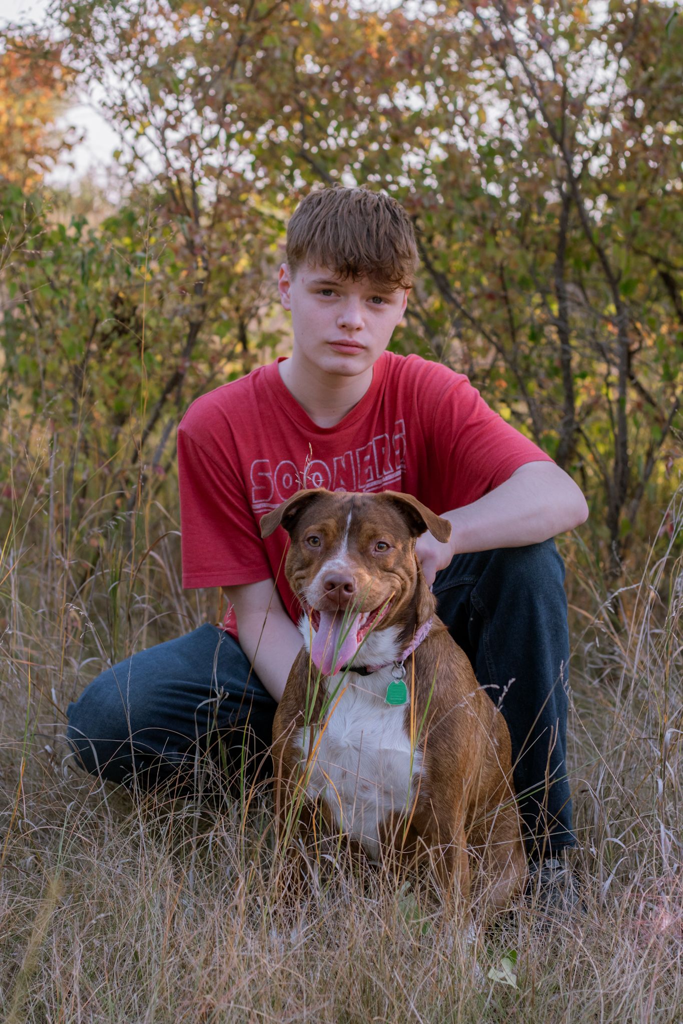High school senior poses with dog while posing for  a senior portrait in Kearney, Nebraska.
