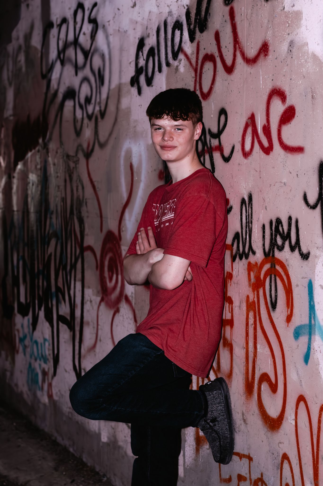 High school senior leans against graffiti wall in Kearney, NE