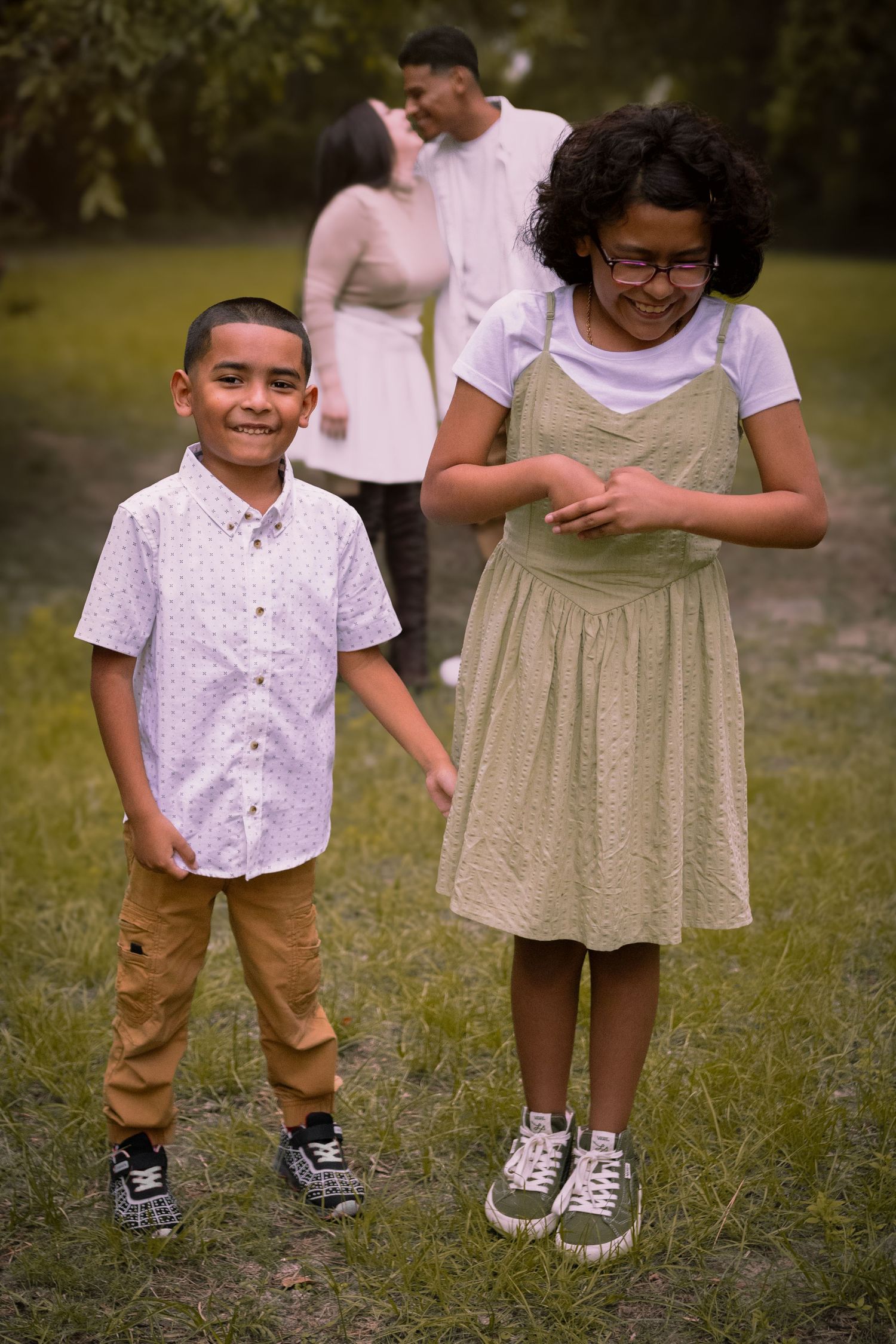 Two children smile and laugh together while standing outdoors.