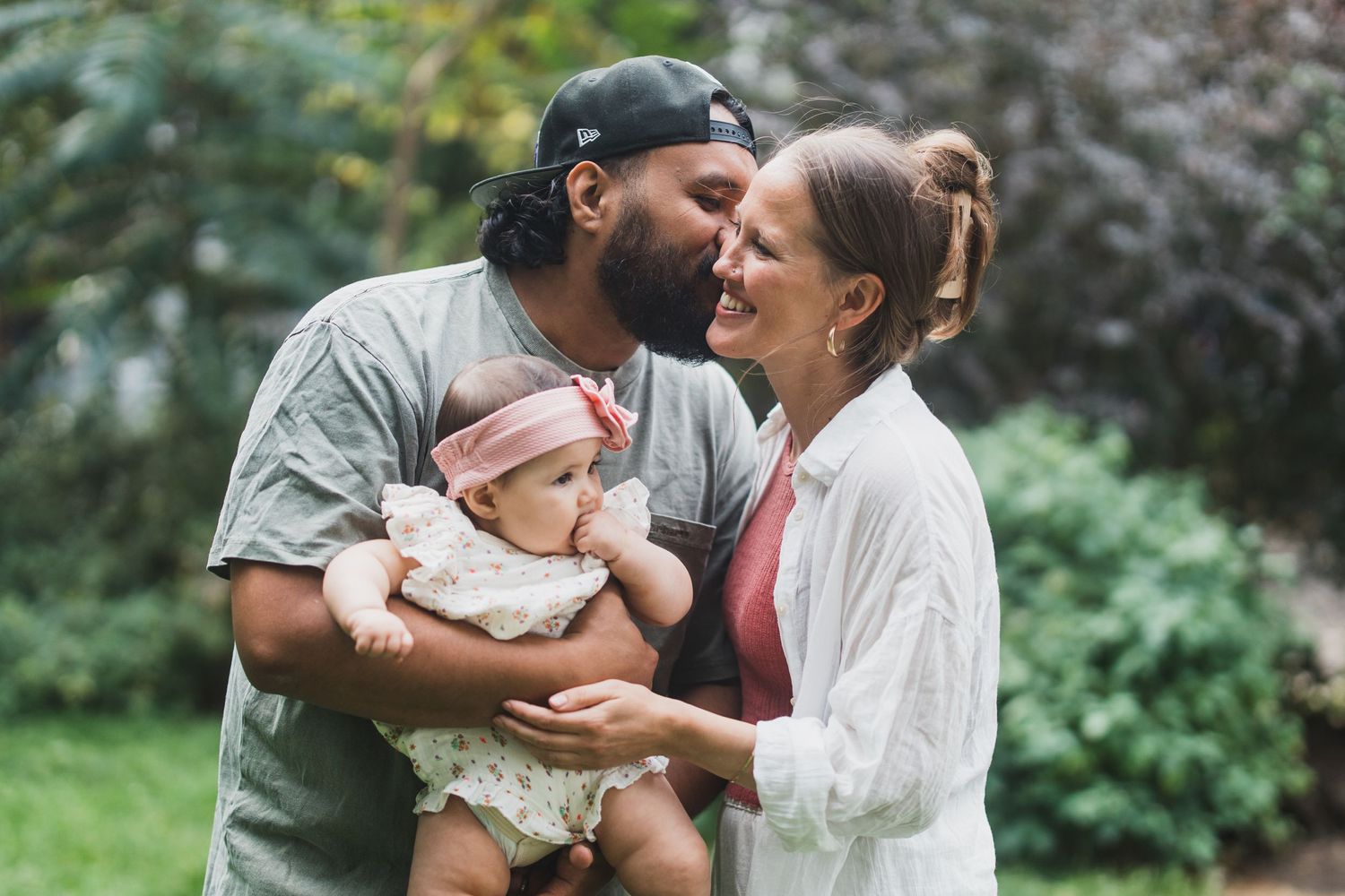 A loving family moment outdoors with a baby in a natural garden setting.