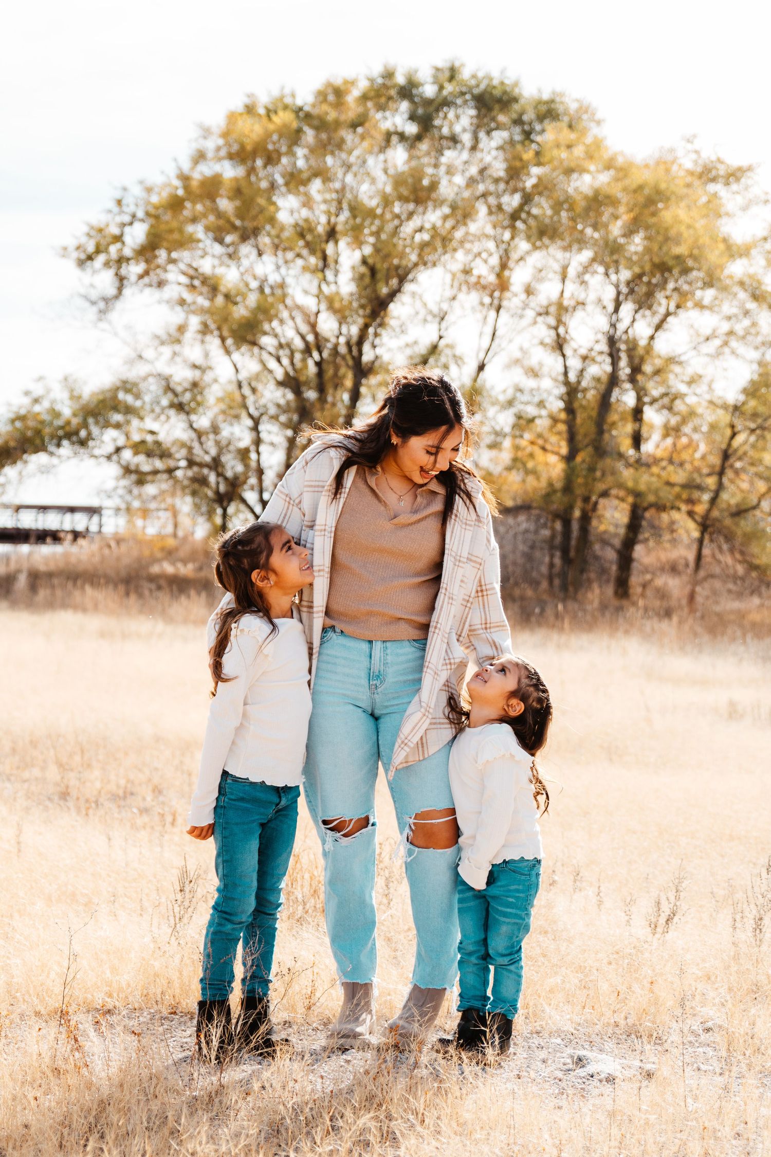 Aunt stands with two nieces and looks lovingly at one another during an affordable family photography session in Kearney, Nebraska.