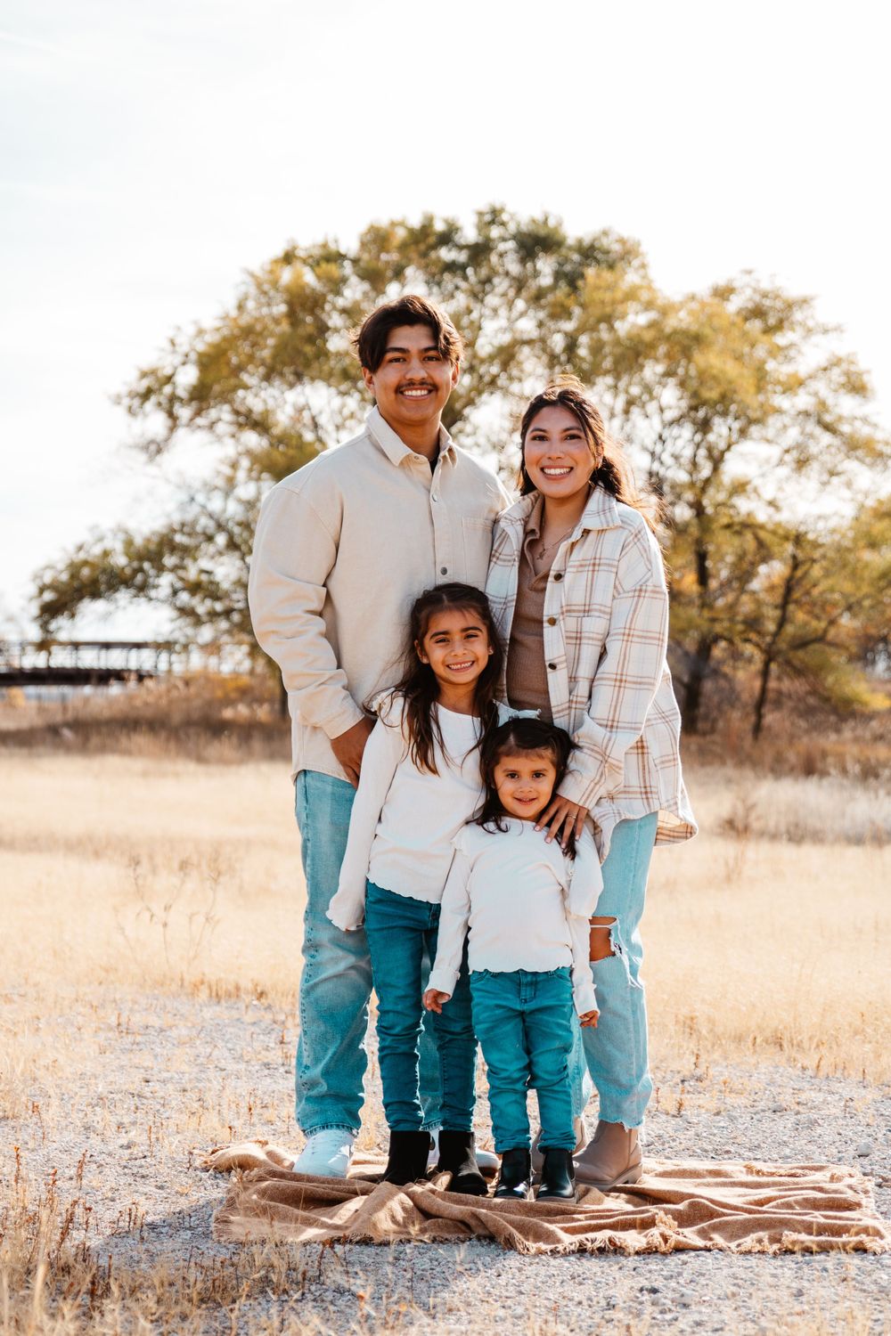 Aunt, uncle, and two nieces stand grouped and smiling outside captured by a Kearney Nebraska family photographer.
