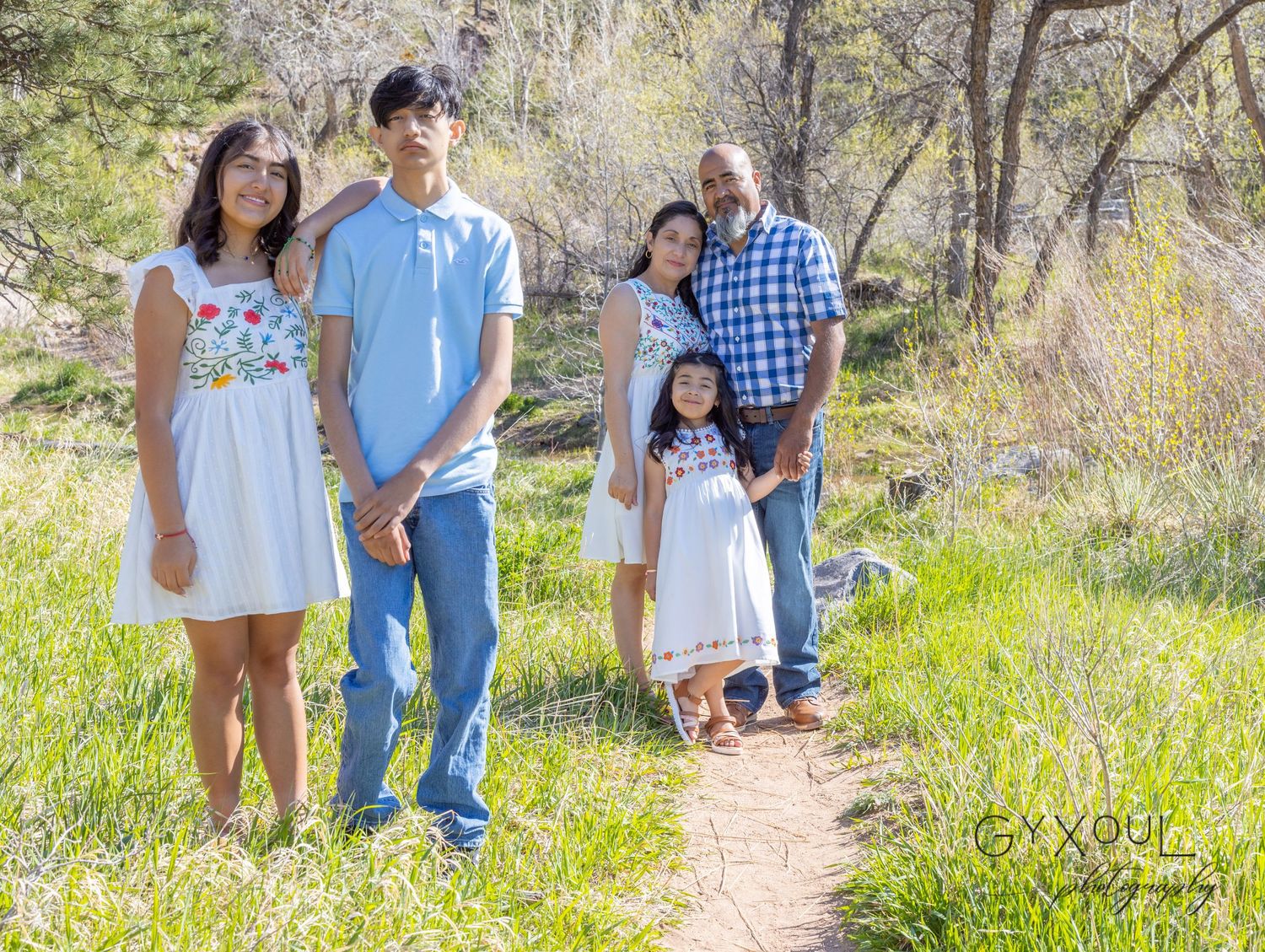 Group poses on nature trail with trees and greenery in background.