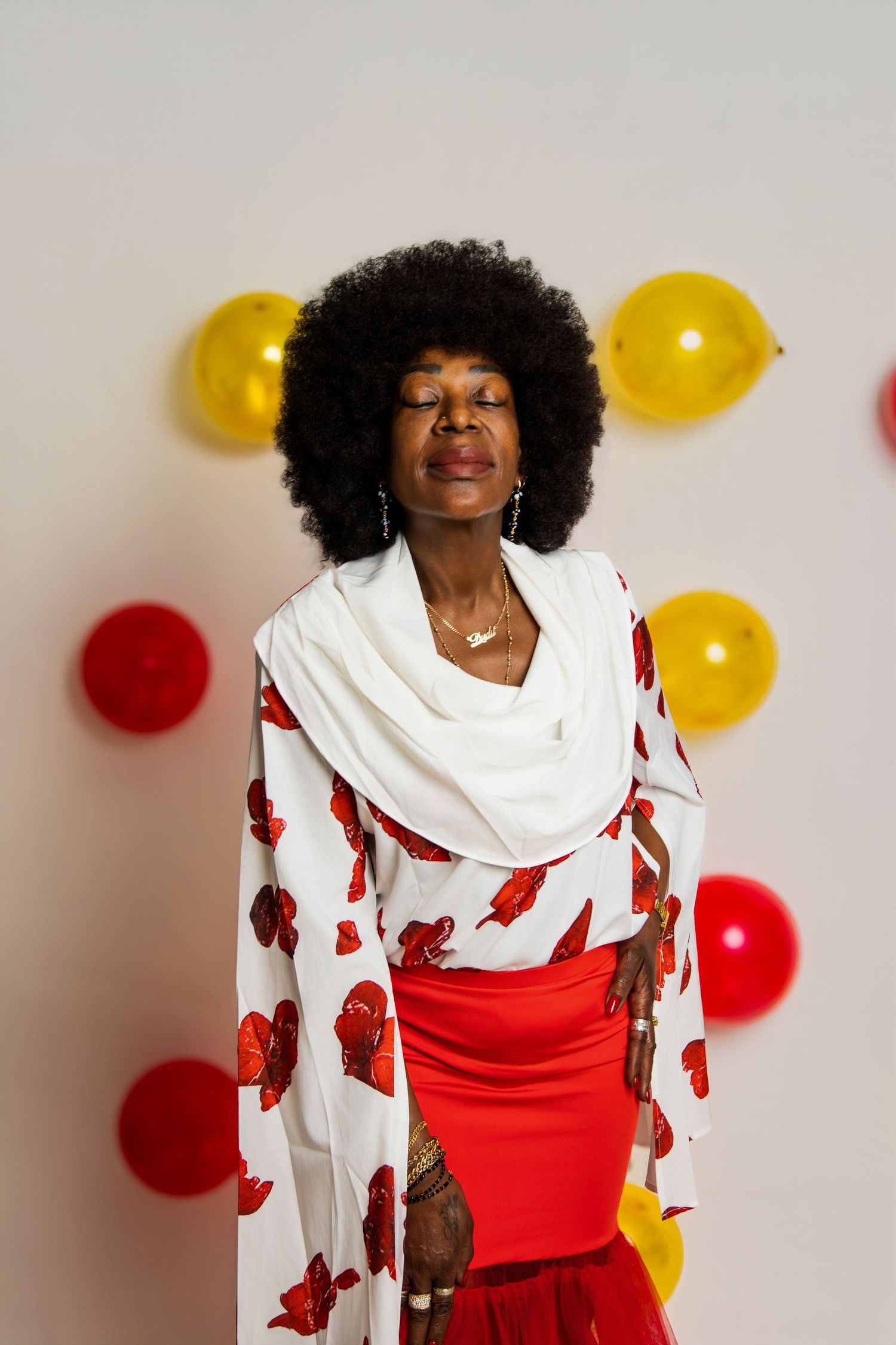 Woman in white and red outfit poses with balloons for festive photoshoot.