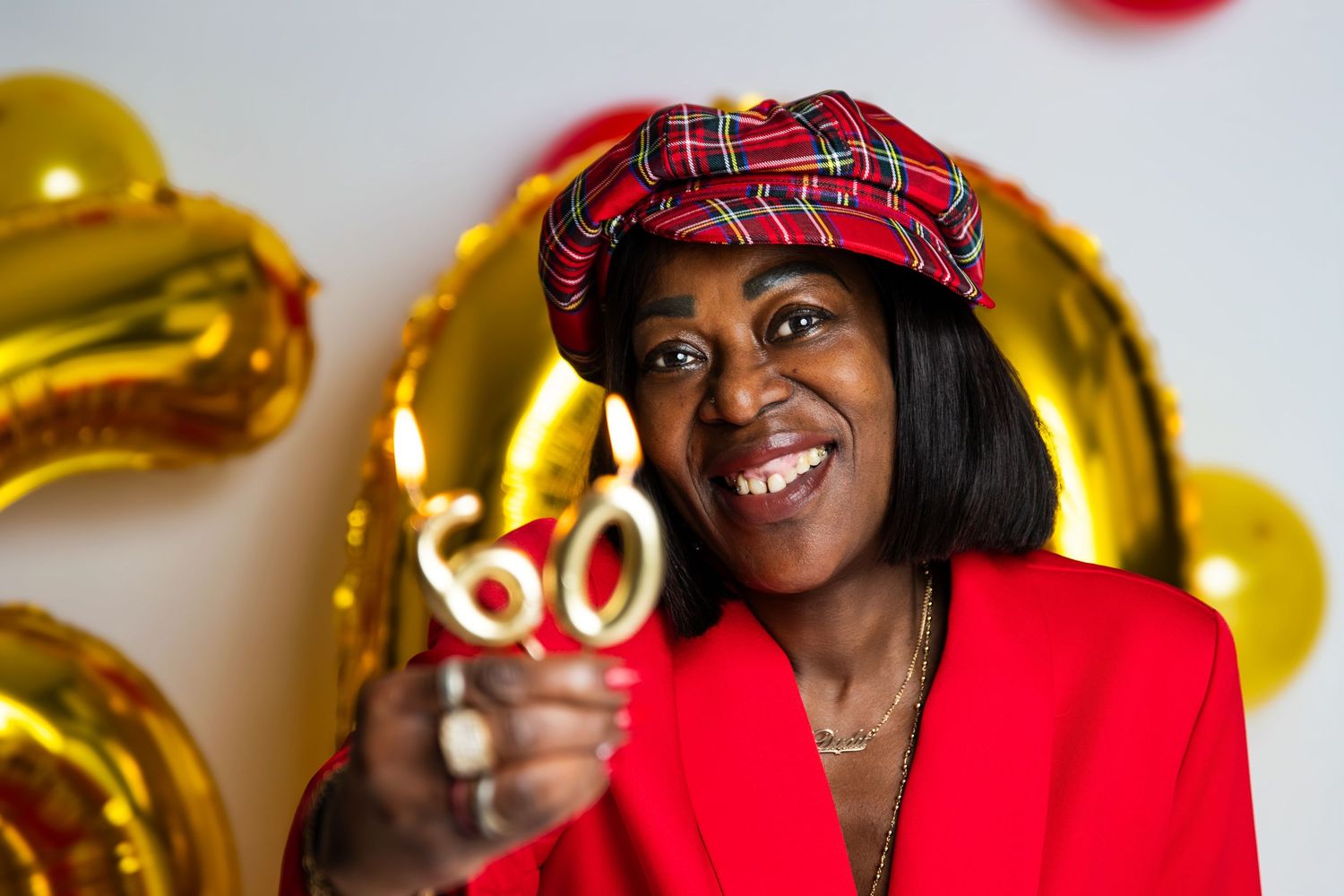 Woman in red hat celebrates with gold balloons and party decorations.