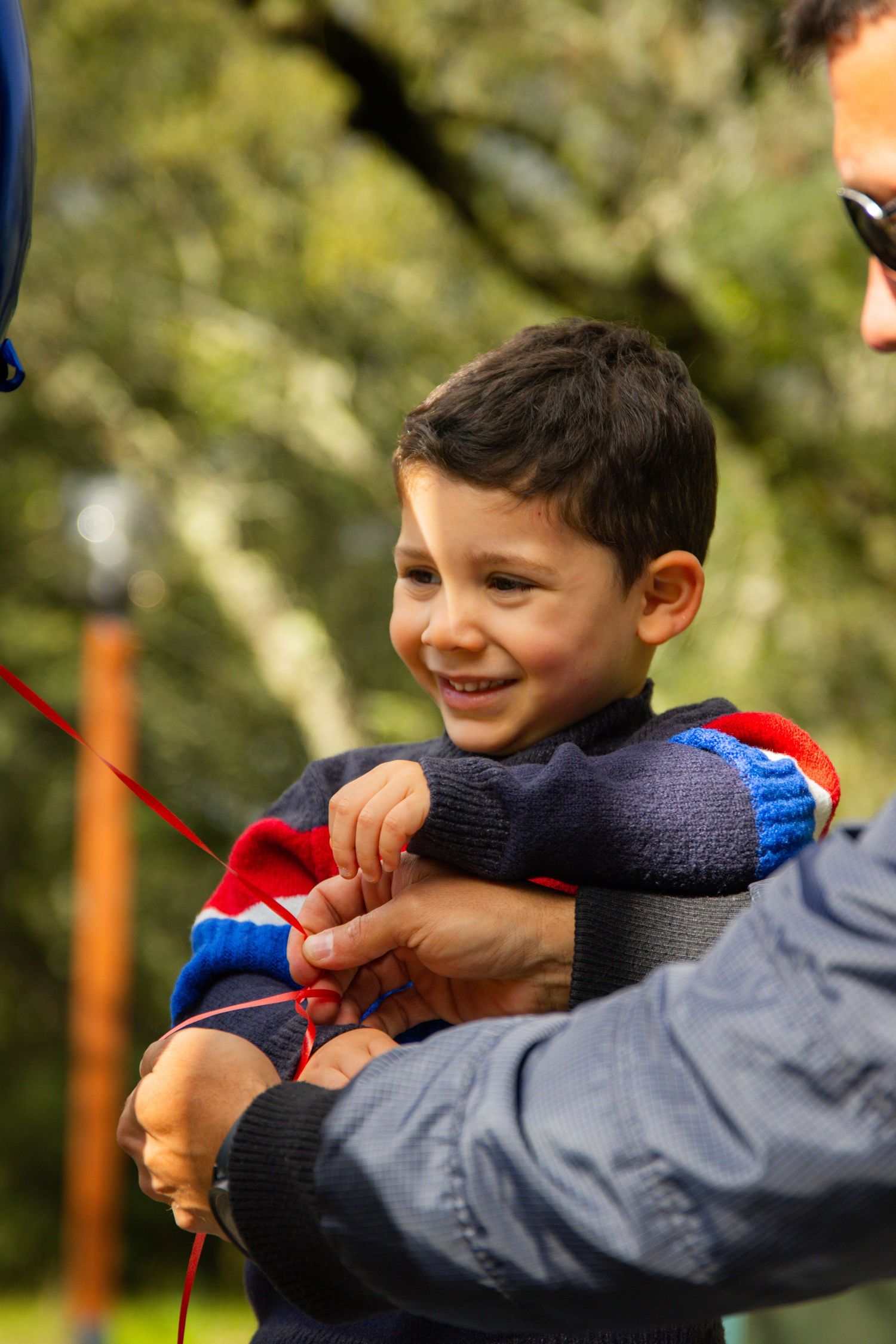 Child in navy jacket playing outdoors on a sunny autumn day.