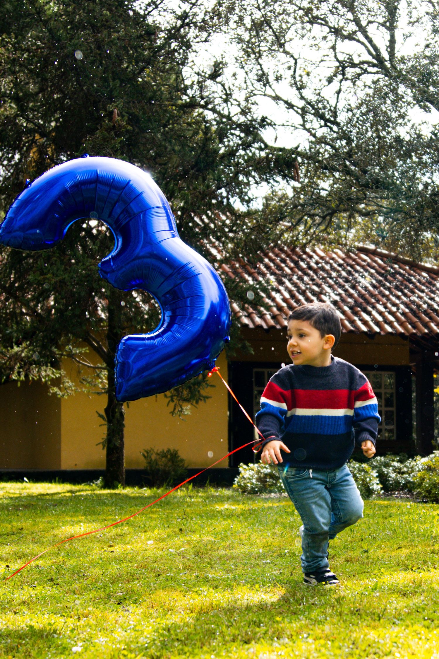 Large blue number balloon being carried across a grassy yard.