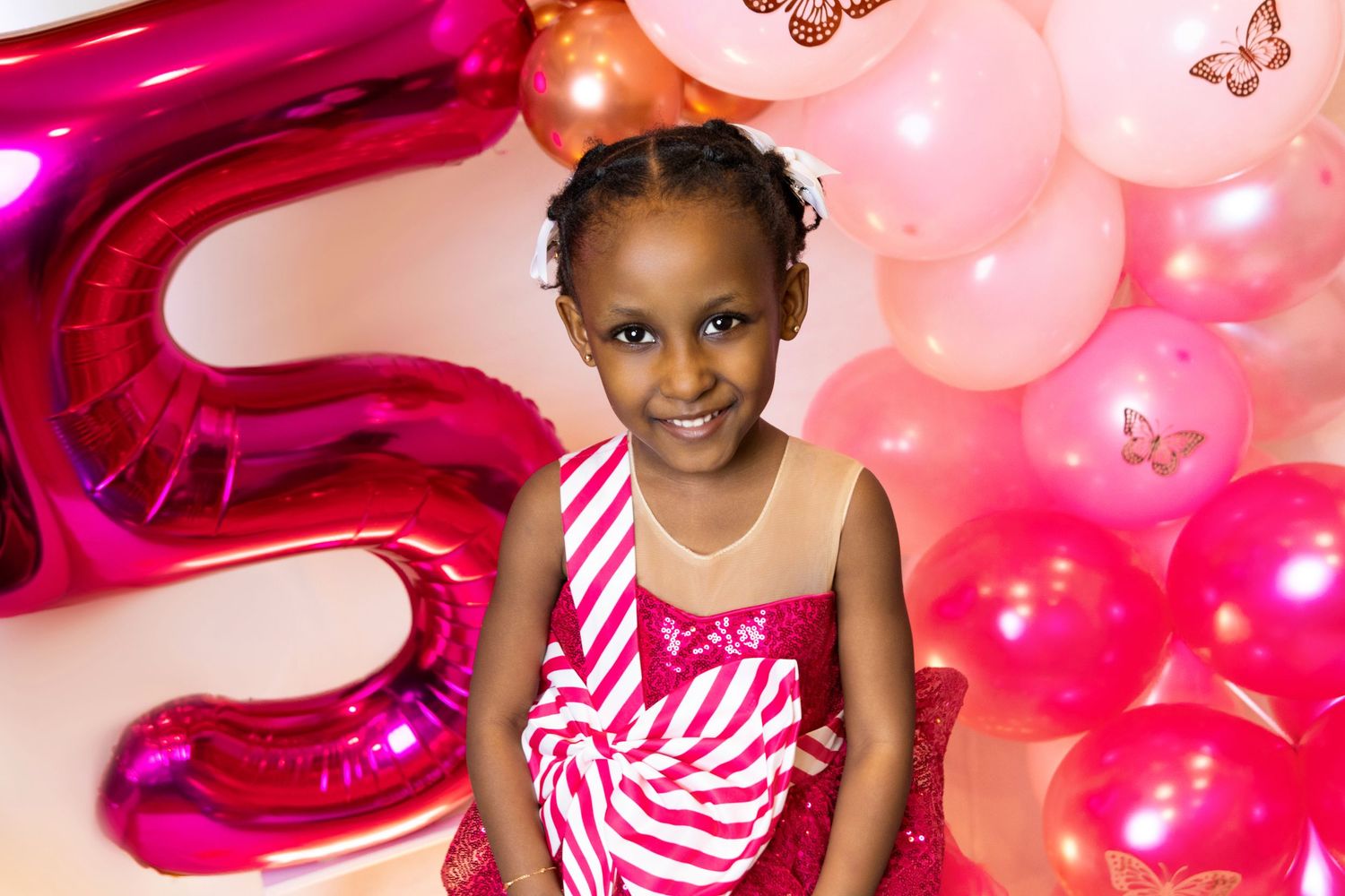 Pink and magenta balloon arrangement with sparkly butterfly decorations for a birthday celebration.