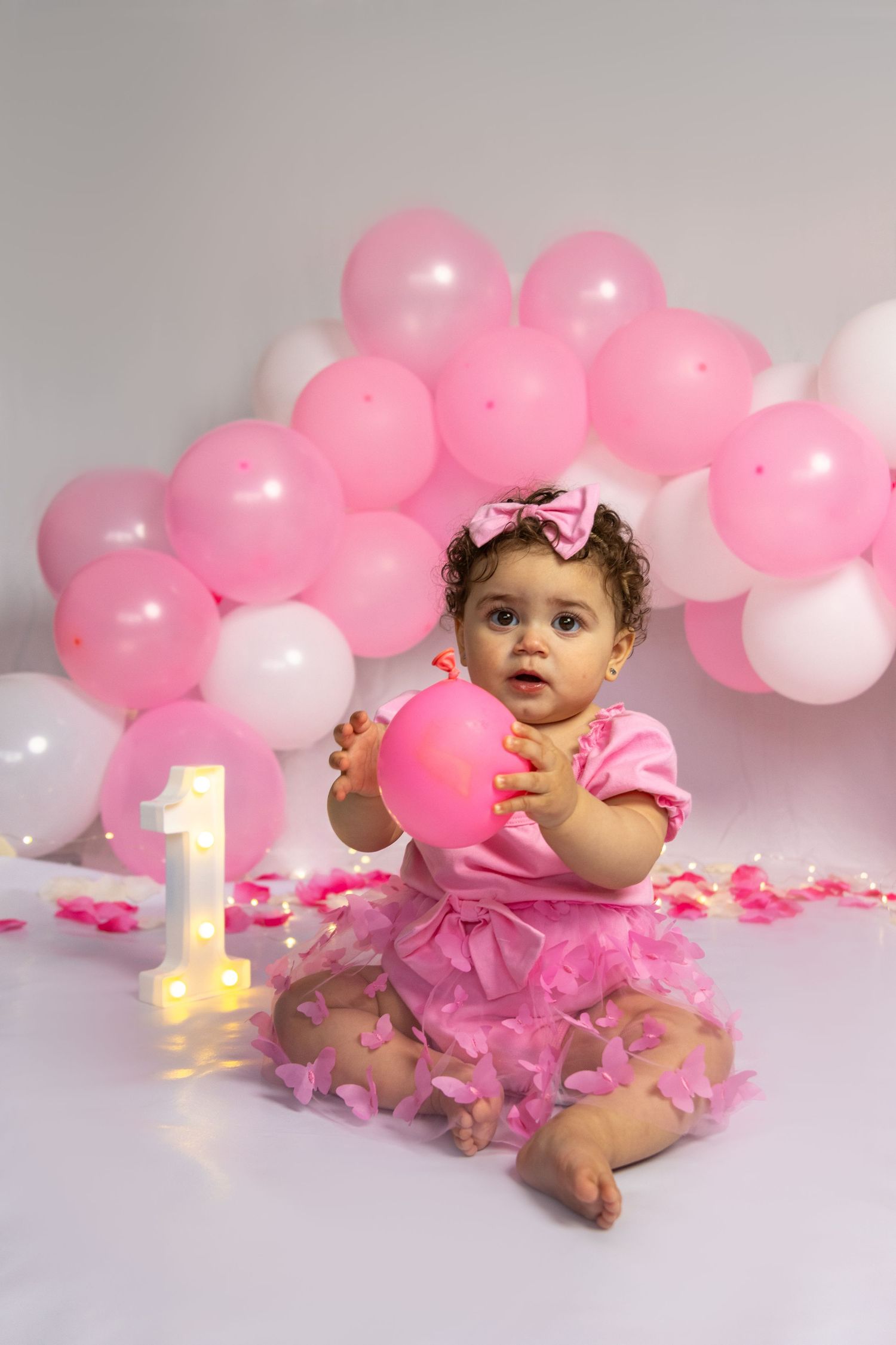 First birthday photo with pink tulle dress and balloon decorations.