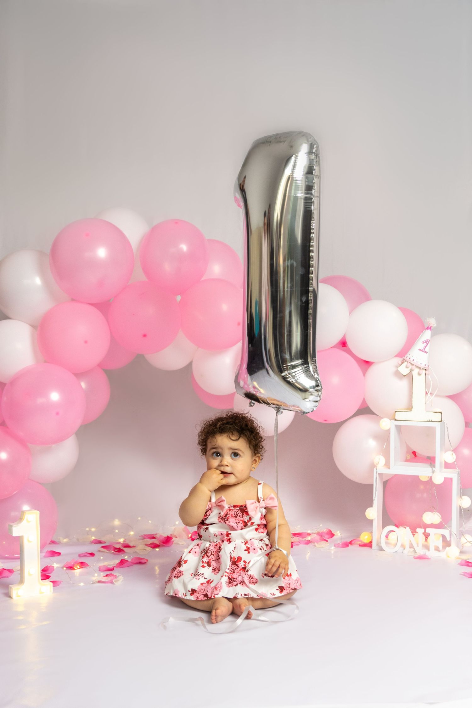 Silver mylar balloons and pink balloon arch for first birthday photoshoot.