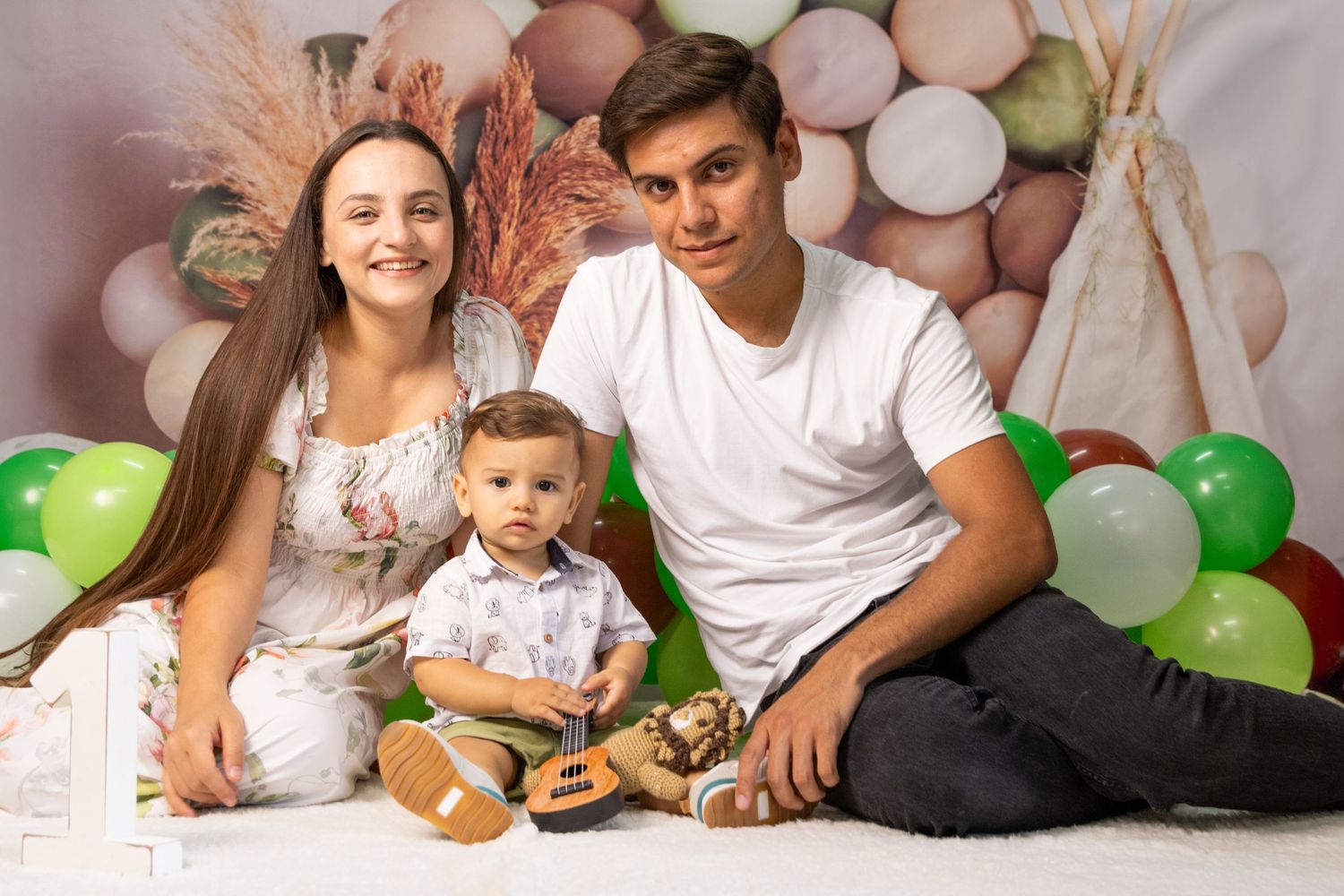 Family portrait setup with green and white balloons and decorative backdrop.
