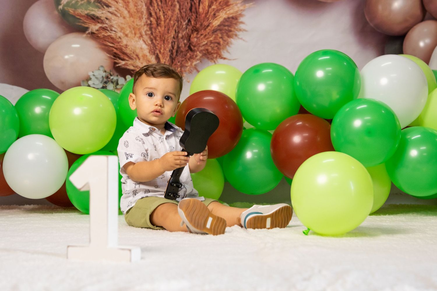 Balloon garland arrangement in green, white and brown tones with pampas grass accents.