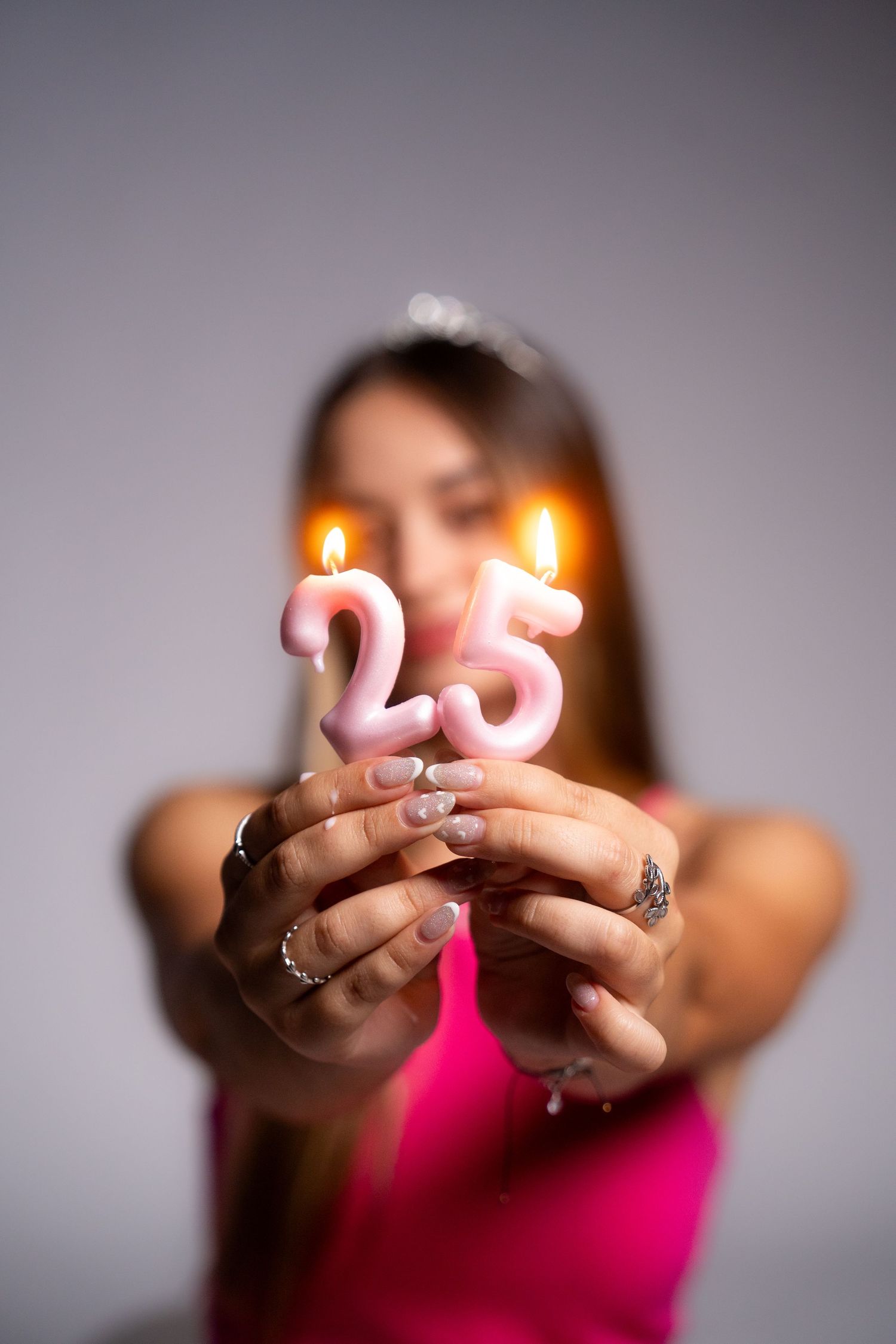 Hands hold glowing number 25 birthday candles in celebratory photo.