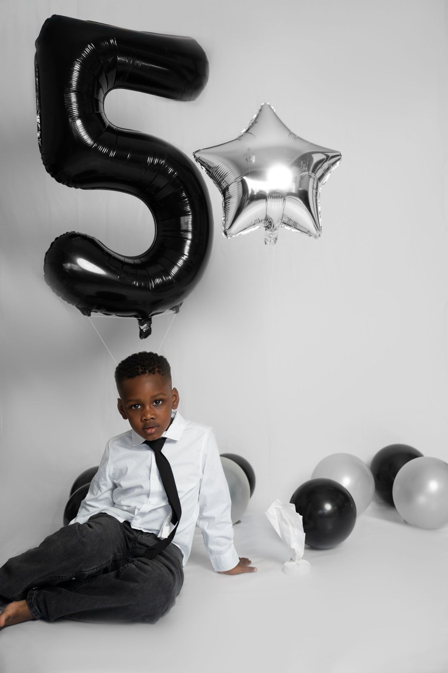 Black and silver birthday photo setup with number 5 balloon and star decorations.