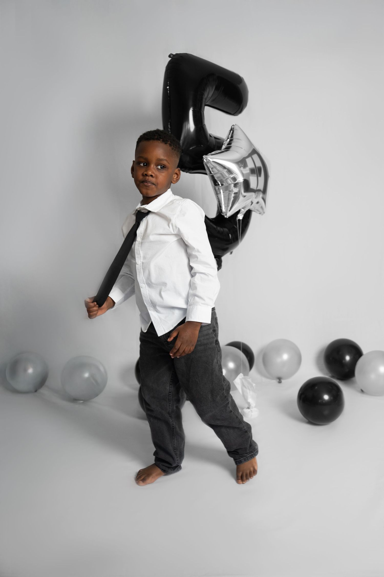 Black and silver balloon decorations with number 5 and star accents against white backdrop.
