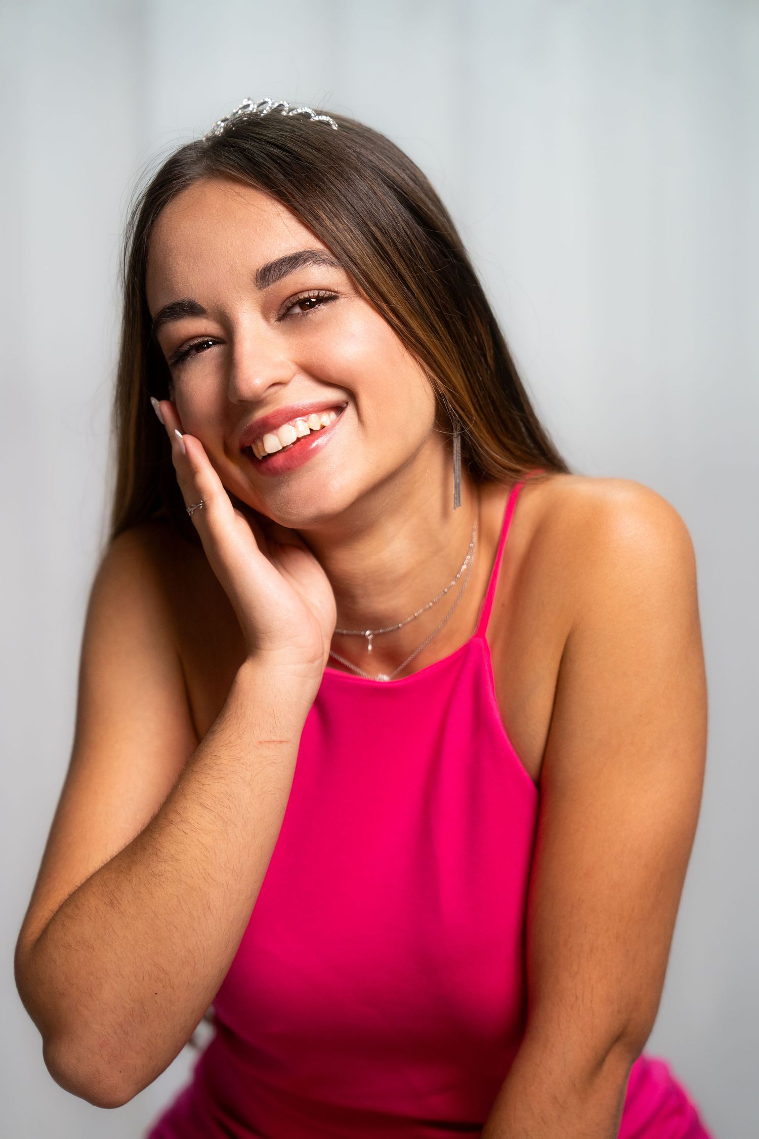 Person in hot pink top poses playfully against light background in portrait series.