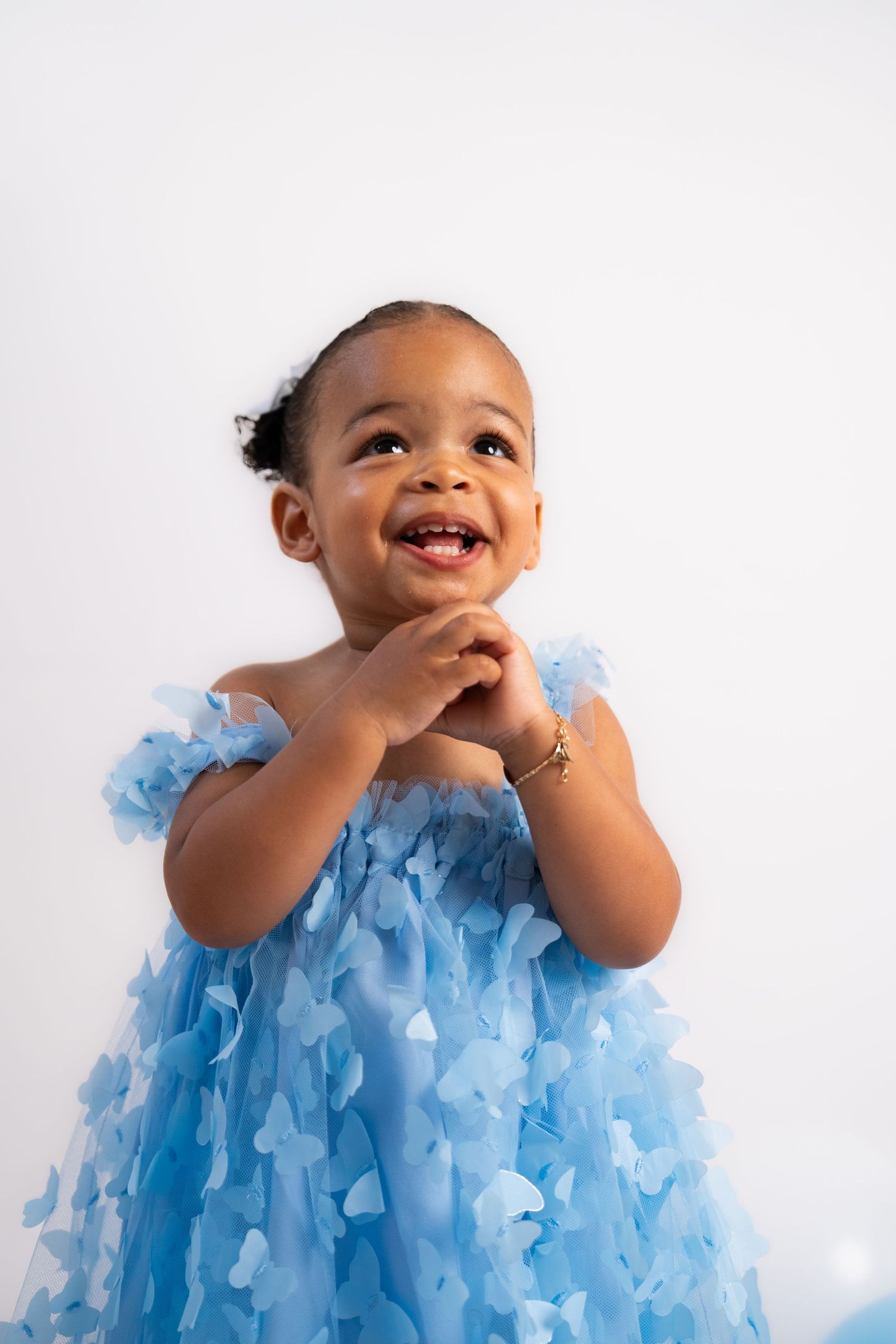 Candid portrait of toddler in blue ruffled dress showing pure joy.