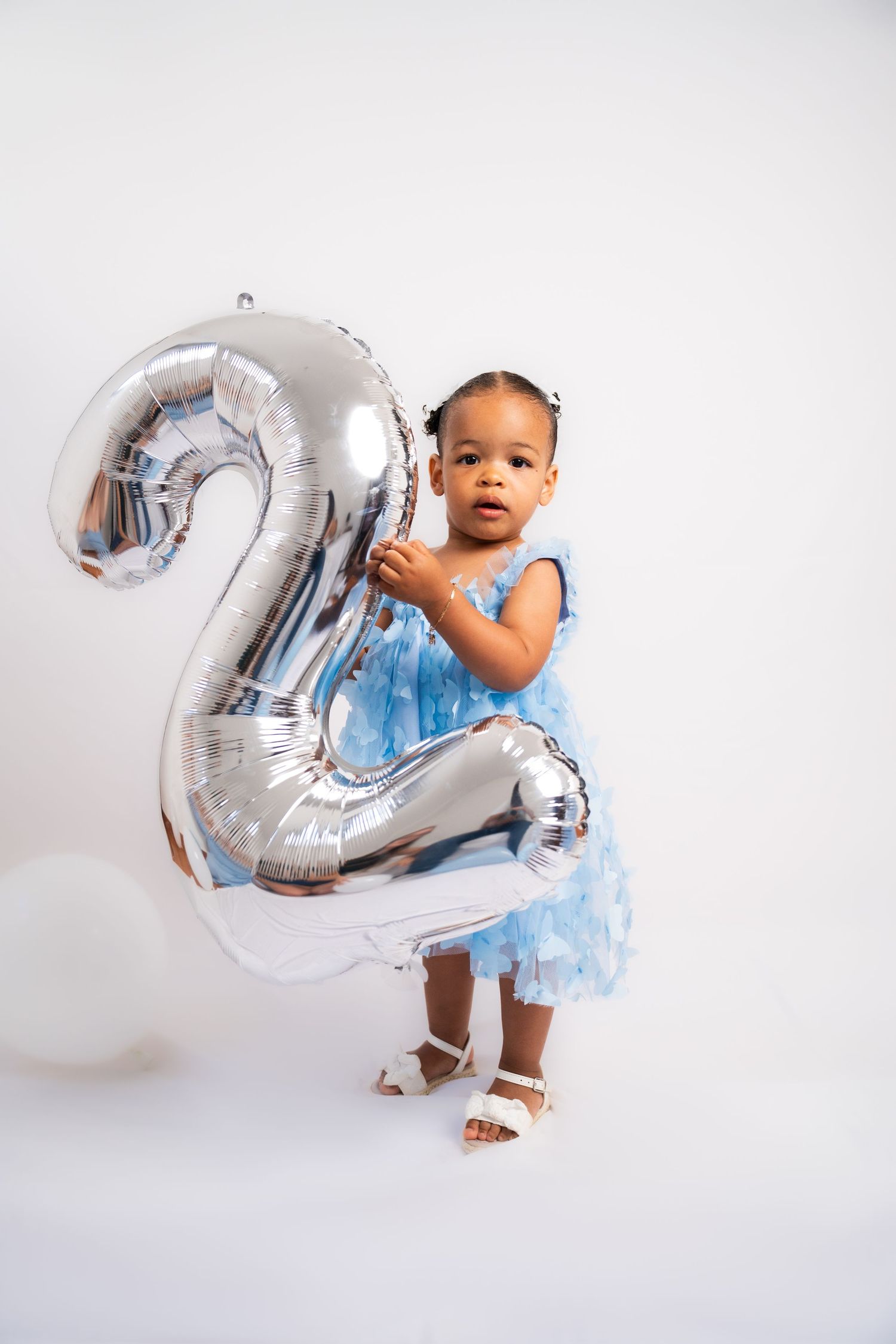 Silver metallic number 2 balloon with light blue party dress against white backdrop.
