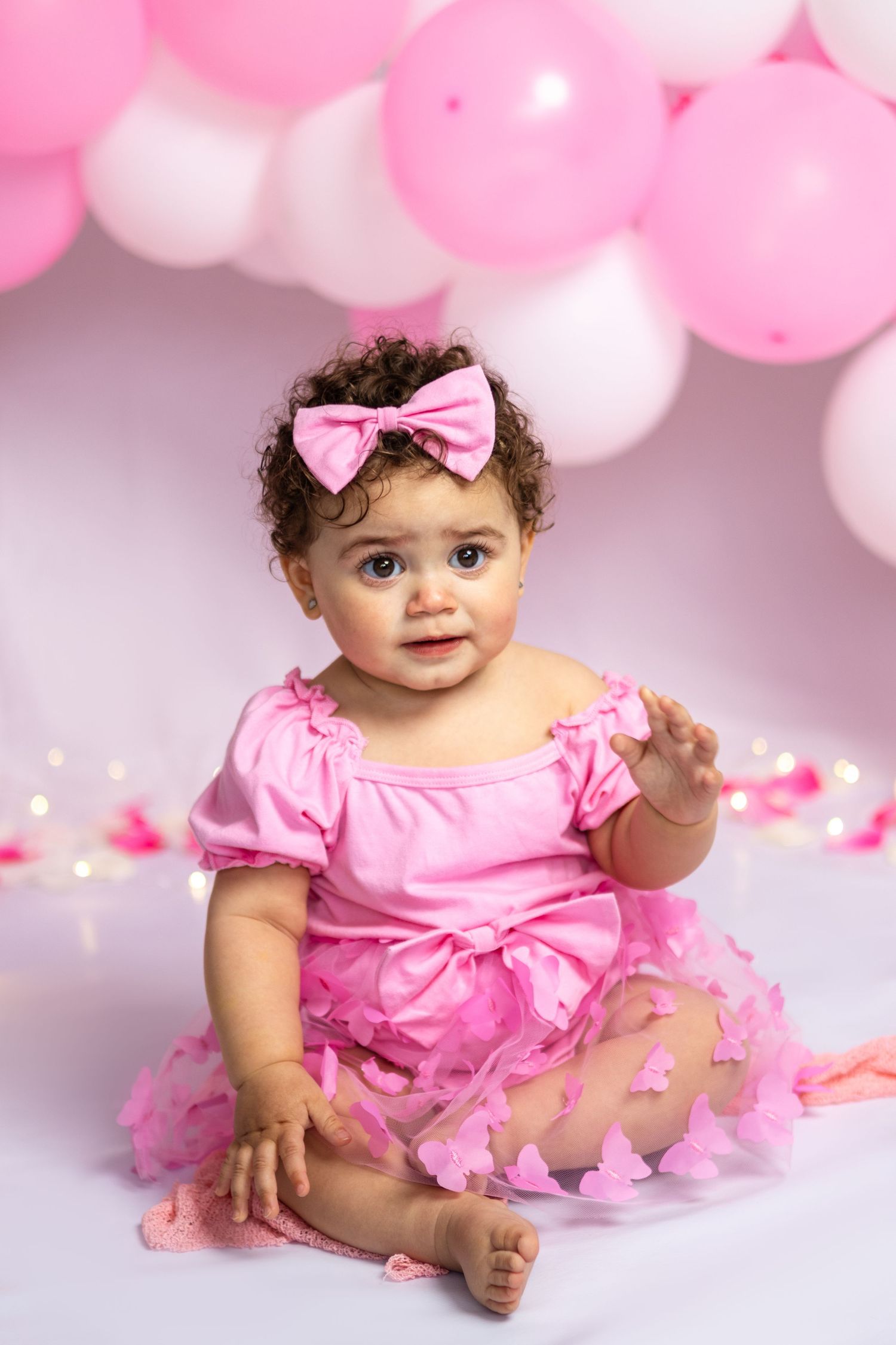 Pink tulle dress and balloon arch setup for first birthday portraits.
