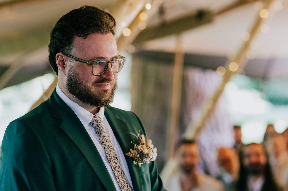 A couple shares an emotional first dance at their wedding reception under an elegant white tent.