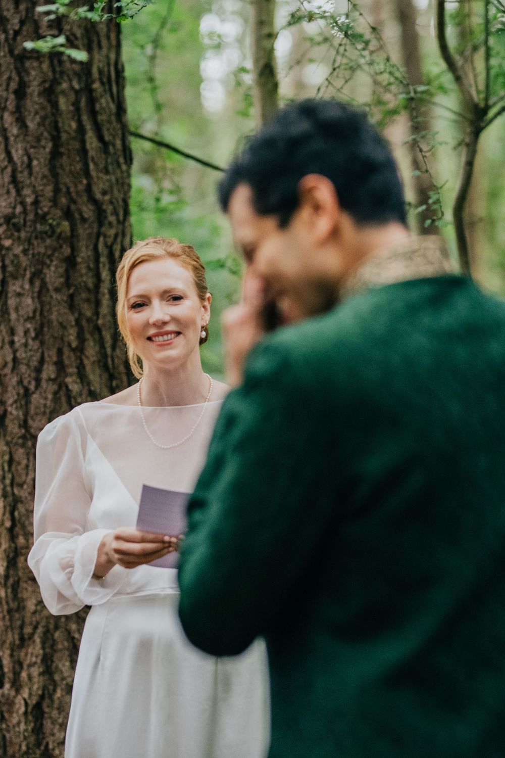 Two people sharing emotional vows during an intimate outdoor wedding ceremony in a forest setting.