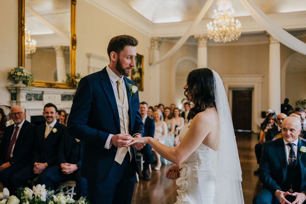 A bride and groom share an elegant first dance at their wedding reception in a grand ballroom with chandeliers.