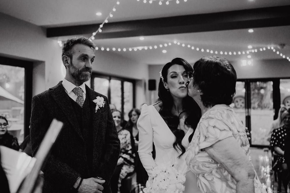 Black and white photo of intimate moments at a wedding reception with string lights and indoor decor.