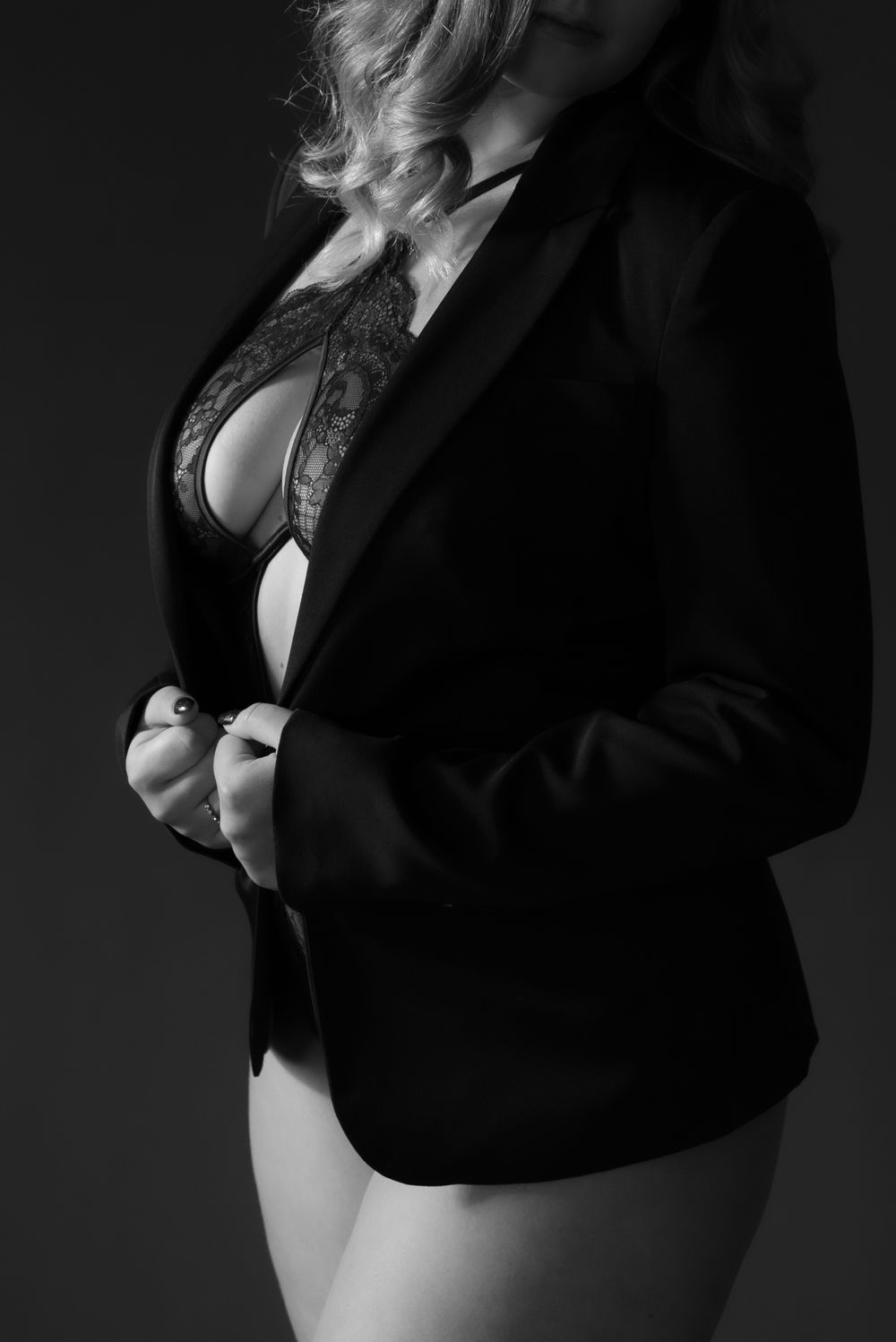 Moody black and white fashion photography featuring dark blazer and light undergarments.