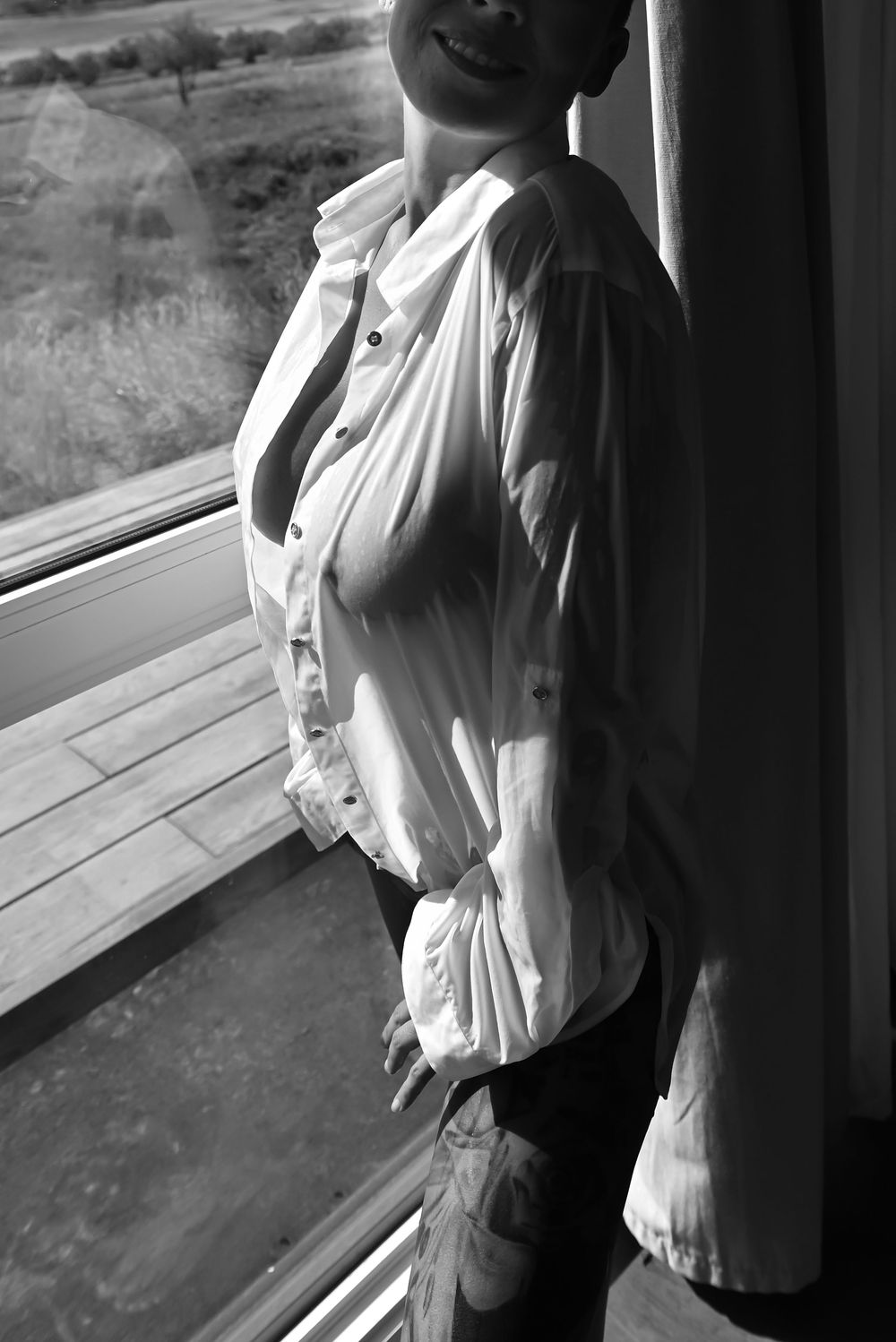 Artistic black and white portrait series by window with flowing white blouse.