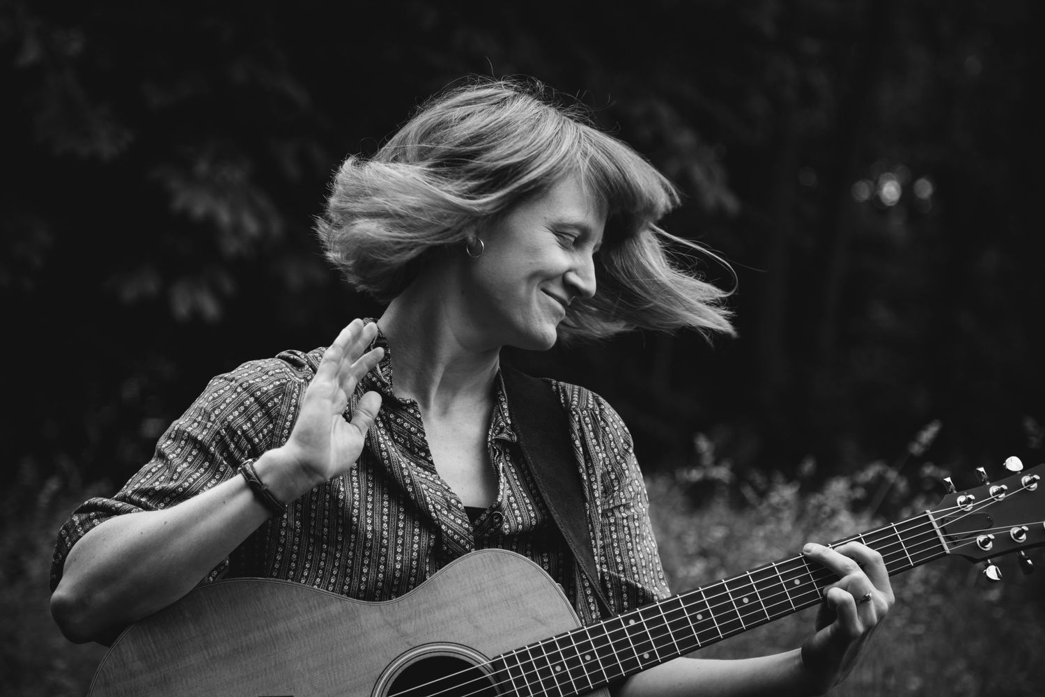 A black and white photo series shows someone playing an acoustic guitar outdoors with dynamic hair movement.