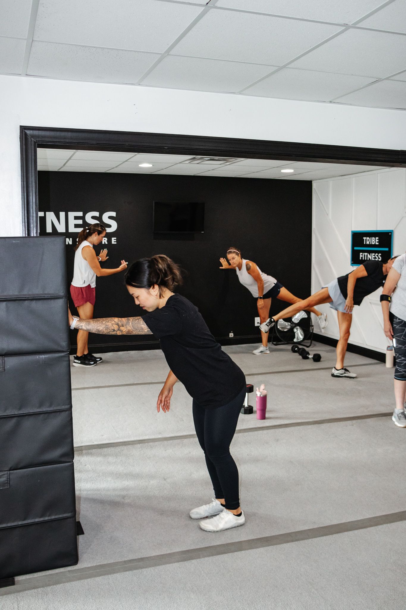 Group fitness class performing curtsy lunges together, instructor guiding at the front of the room.