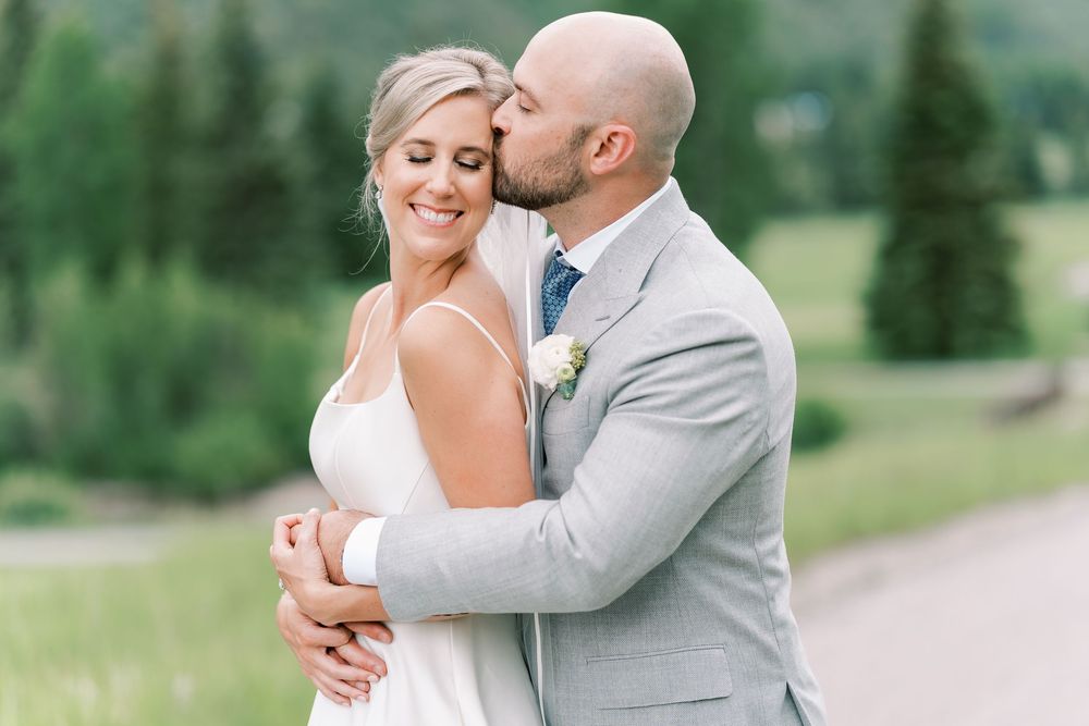 A couple shares an intimate moment while dancing outdoors in a beautiful natural setting with lush greenery.