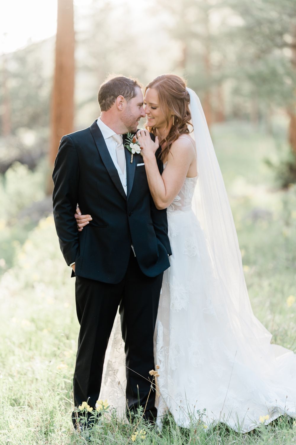 Romantic wedding portrait of couple sharing intimate moment in sunlit forest setting.
