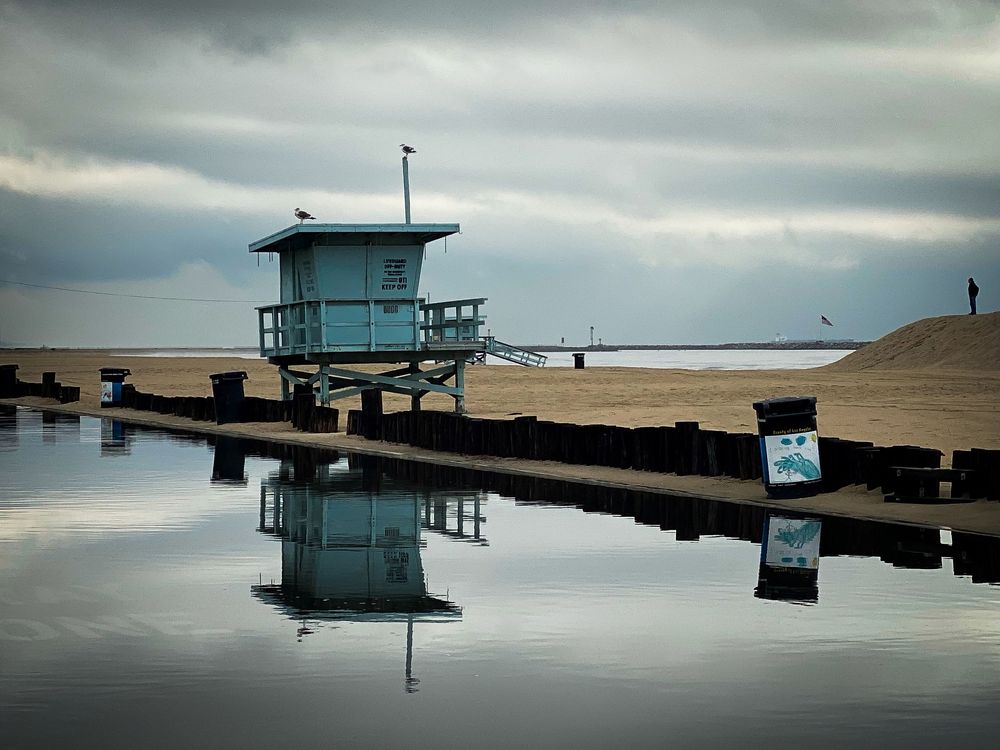 Moody waterfront scene with docks and floating structures reflecting in still water.