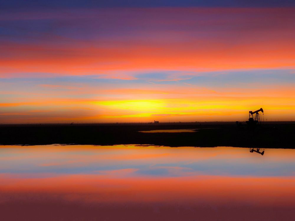 Vibrant sunset sky with layers of purple, orange and blue colors reflected over a calm body of water.