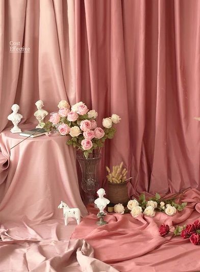 Elegant pink silk drapery with roses, small sculptures and decorative elements for photography.