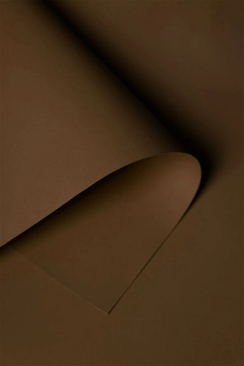 Abstract curved shadow on brown paper creating minimalist artistic composition.