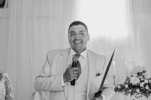 A joyous wedding celebration with toasts being made at a reception table under warm lighting.