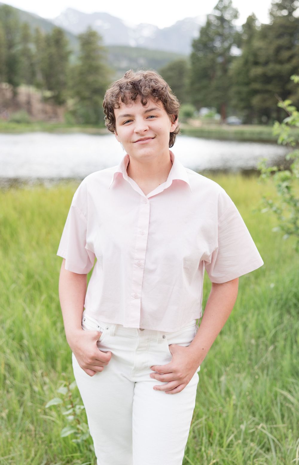 Three portrait photos taken outdoors in a grassy field with mountains and trees in the background.