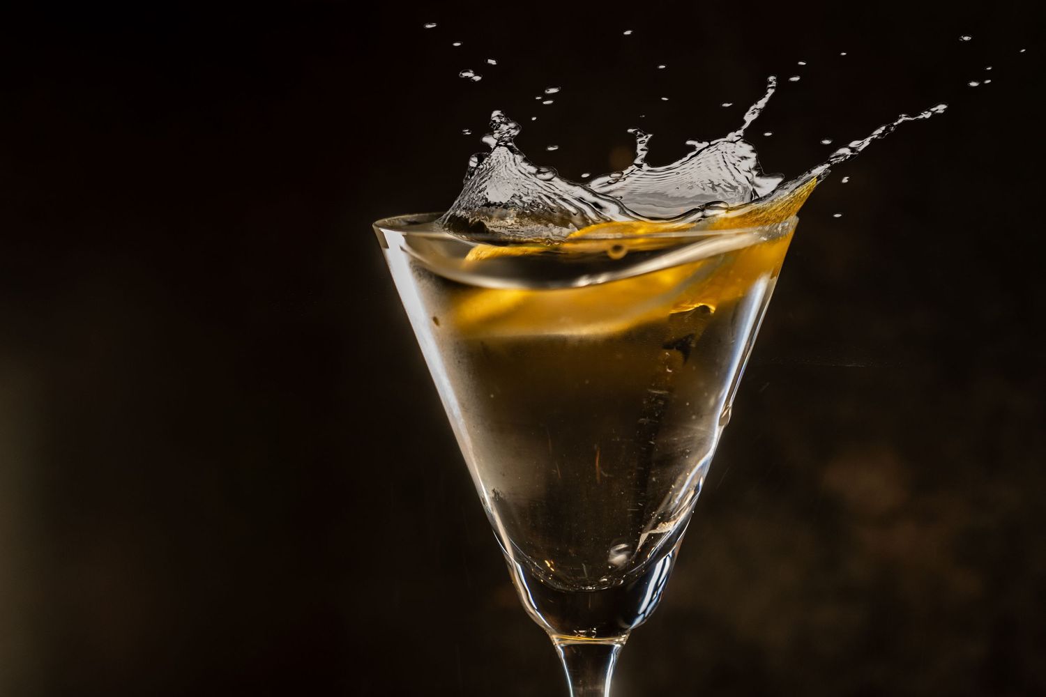 Martini glasses filled with golden cocktails on a dark reflective surface, new menu drink photography.