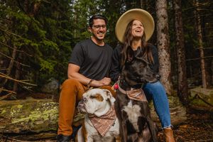 Group enjoys fall hike in forest with their happy dogs on leashes along wooded trail in autumn.