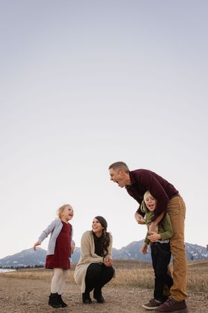 A family shares a joyful moment together outdoors with mountains in the background during golden hour.