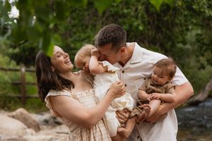 A joyful family shares a tender moment together by a stream on a sunny day in nature.