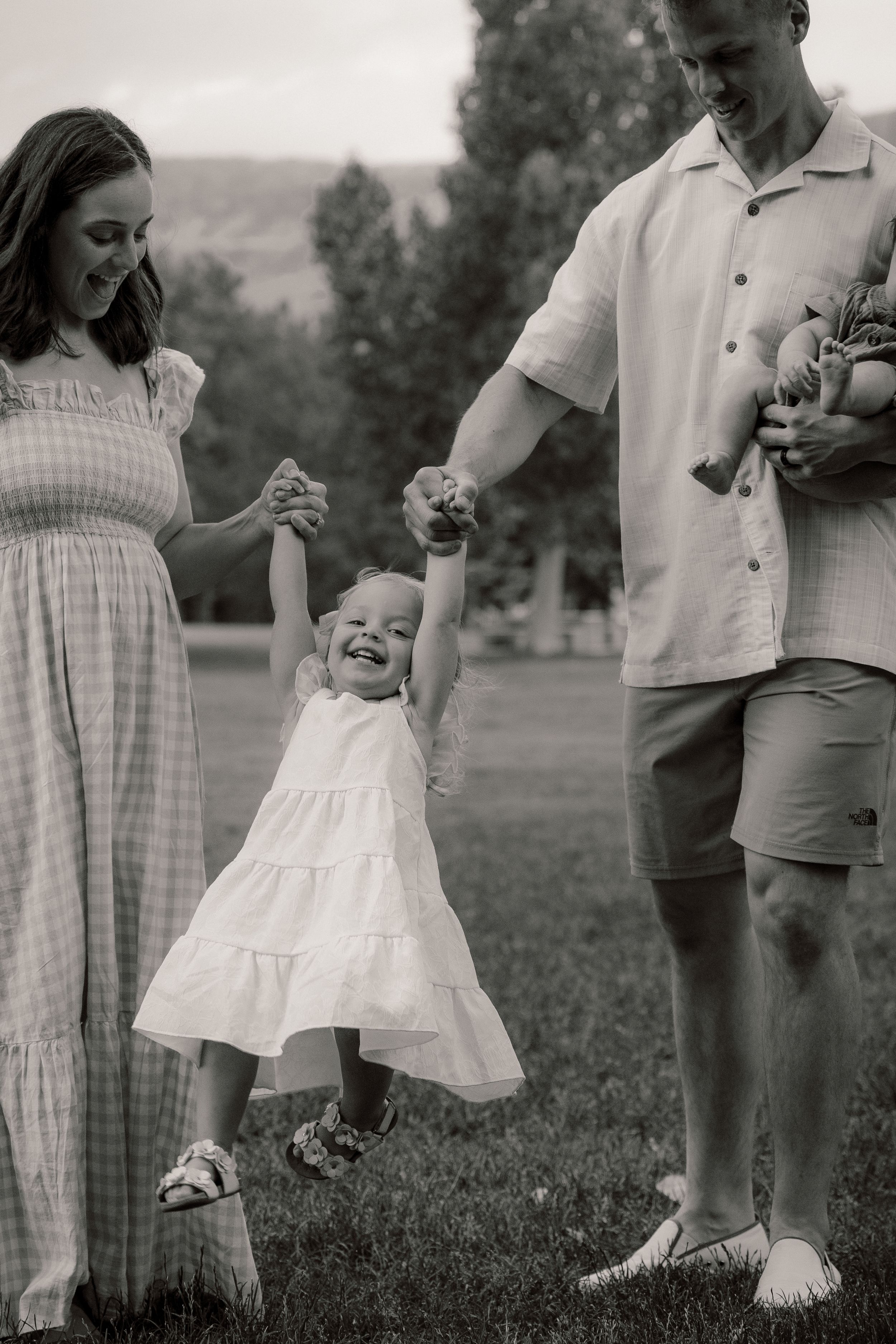 Black and white series of cropped photographs showing small child playing in a checked dress on grassy field.