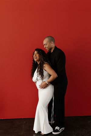 Joyful couple shares intimate candid moments against a vibrant red wall and dark floor in a photo sequence.