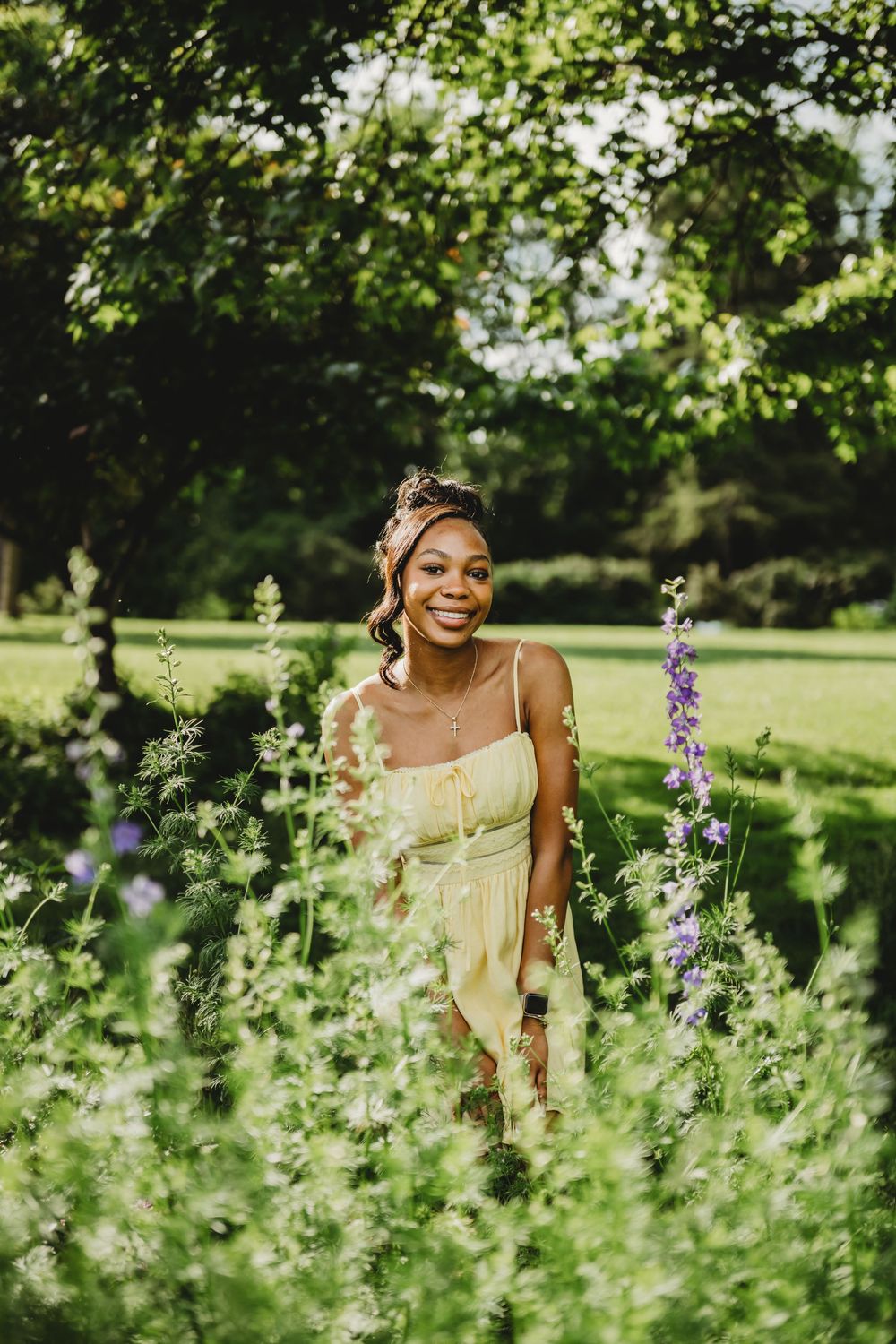 A joyful photoshoot in a lush garden setting with wildflowers and greenery on a sunny summer day.