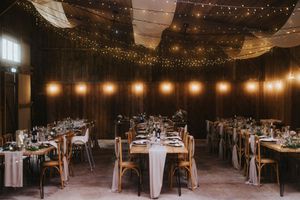 A rustic barn wedding reception venue decorated with romantic string lights and white table settings shows warmth and elegance.